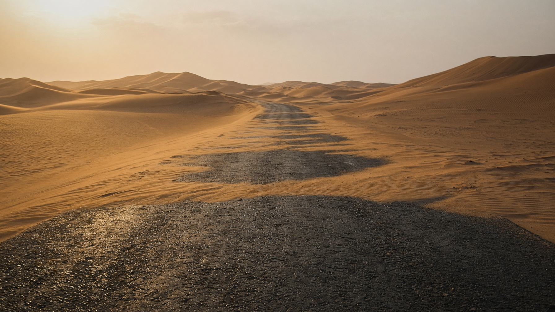 Une route d’asphalte qui s’enfonce dans les dunes.
